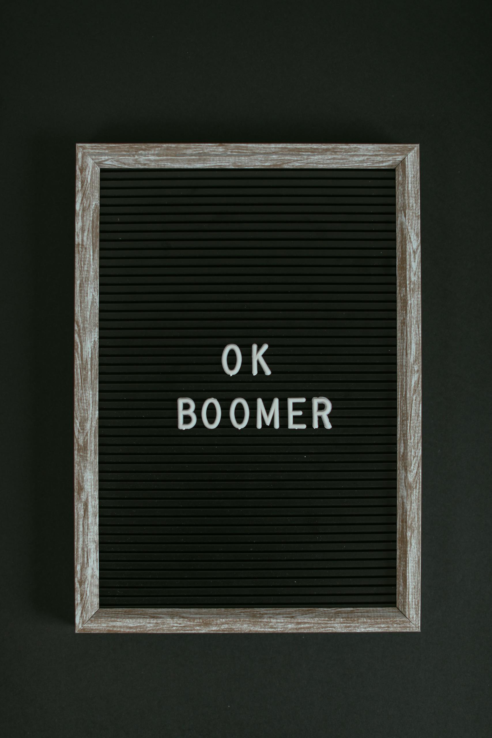 A minimalist letter board displaying the phrase 'OK Boomer' against a black surface.